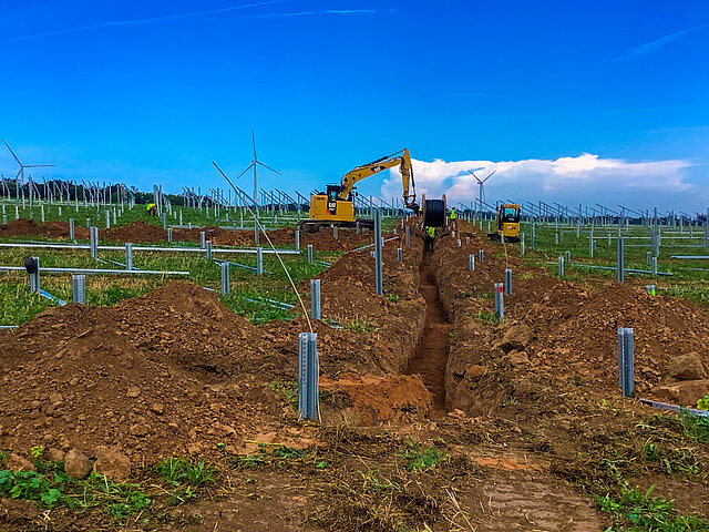 An excavator is used to lay cable routes in a solar park.